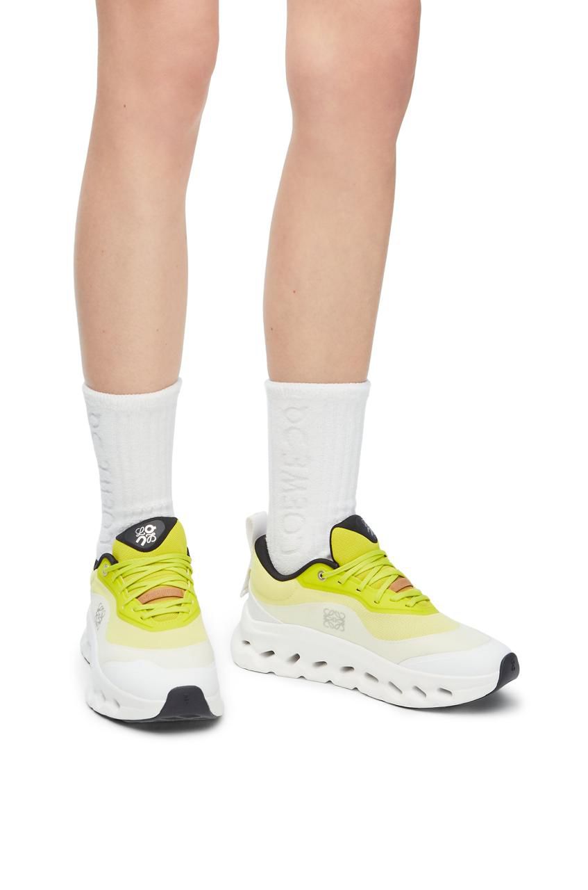 WhatsApp_Image_2024-09-09_at_09.47.26 | AE JERSEY Person wearing bright yellow athletic sneakers and white crew socks, viewed from the front/low angle.