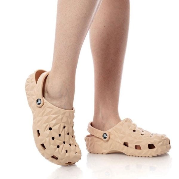 Peach-colored geometric clogs with back strap on a person’s feet.
