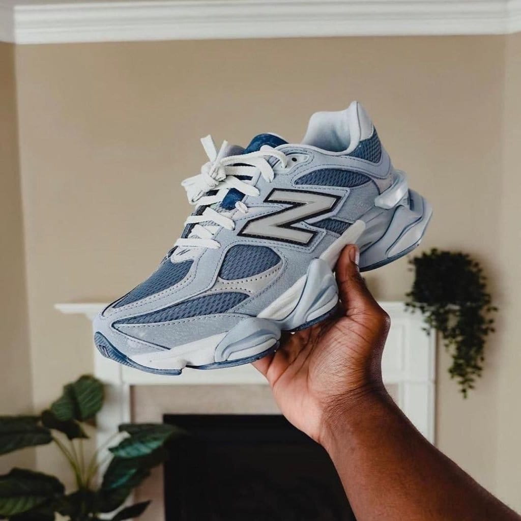 WhatsApp_Image_2024-10-26_at_16.18.05 | AE JERSEY Hand holding a light blue New Balance sneaker indoors, showing the side with the large N logo