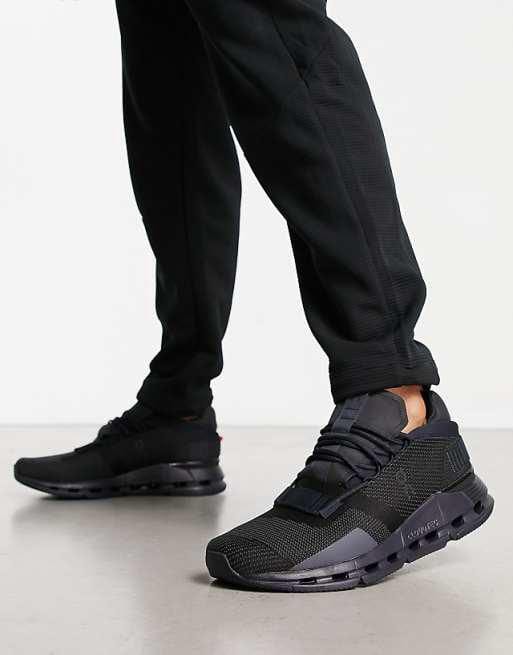 WhatsApp_Image_2024-11-06_at_11.22.29 | AE JERSEY Close-up of black running shoes with a chunky sole, worn with black joggers, as the person takes a step forward.