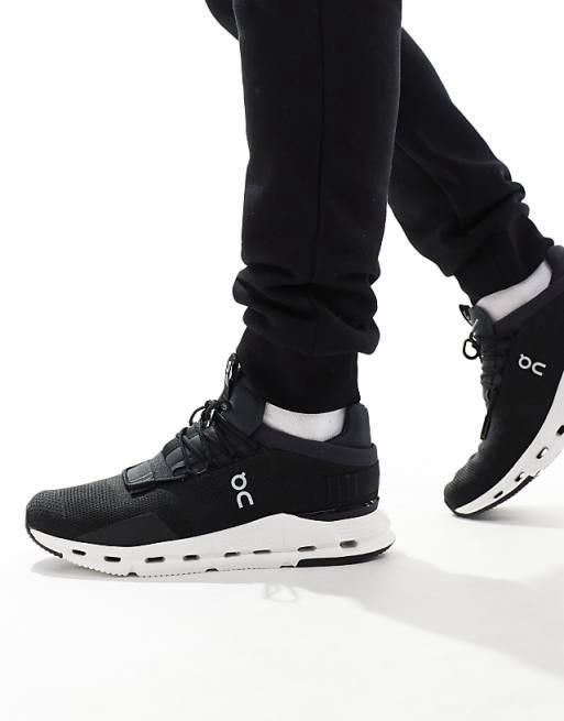 WhatsApp_Image_2024-11-07_at_12.03.06 | AE JERSEY Close-up of black On running sneakers with white soles being worn by a person walking.