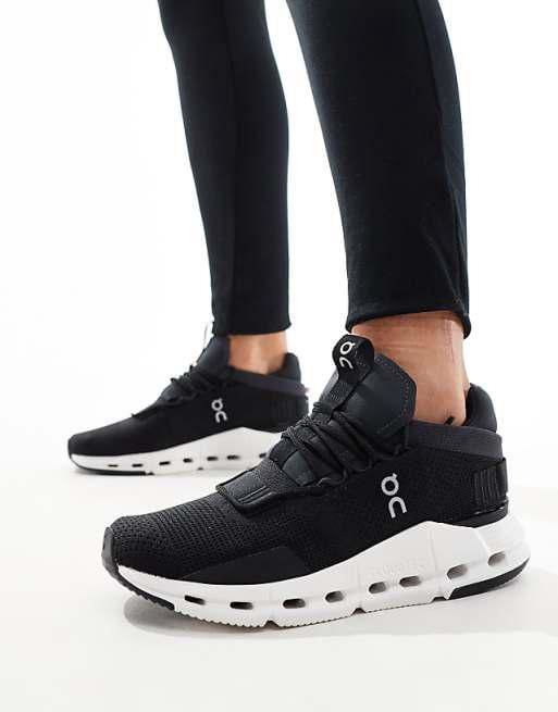 WhatsApp_Image_2024-11-07_at_12.03.07 | AE JERSEY Black athletic sneakers with white chunky sole and On logo, worn with black leggings in a standing pose.