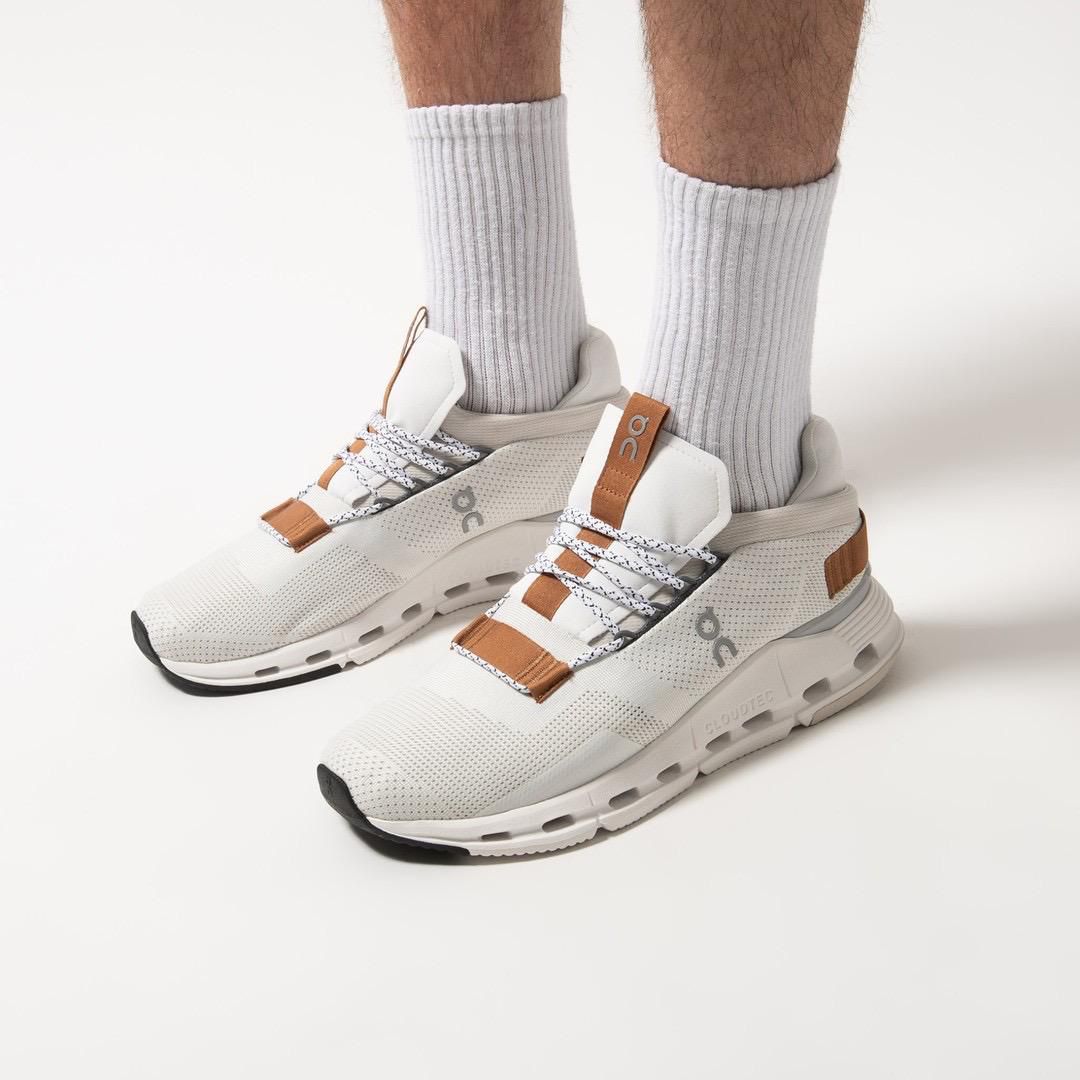 WhatsApp_Image_2024-11-07_at_14.08.37 | AE JERSEY White athletic sneakers with tan-brown accents worn with light gray ribbed socks on a pale backdrop (showing a sporty lifestyle product).