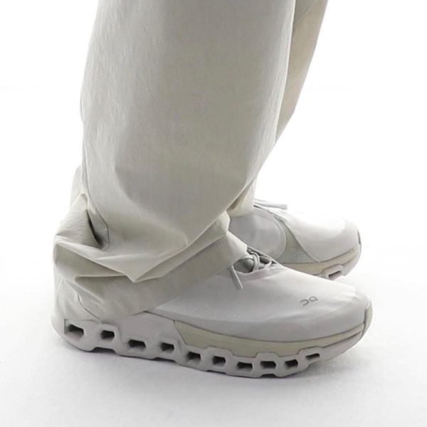 Close-up of white athletic shoes with a hollow, segmented sole and light gray accents.