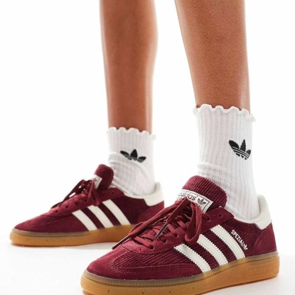 Person wearing maroon Adidas sneakers with white stripes and gum soles, paired with white ribbed socks.