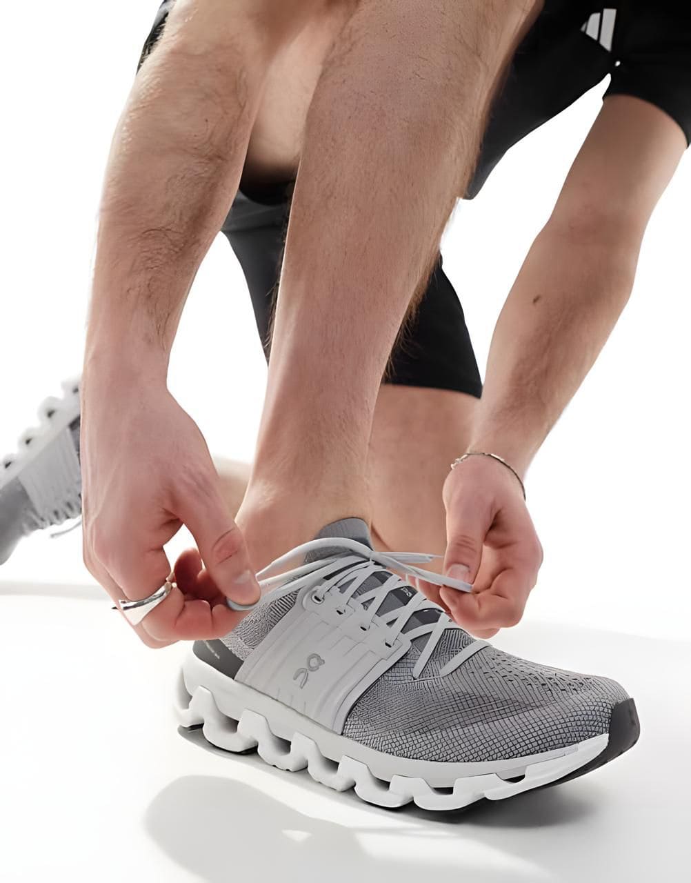 WhatsApp_Image_2025-01-13_at_21.03.18 | AE JERSEY Close-up of hands tying the laces of a gray athletic shoe with a white sole.
