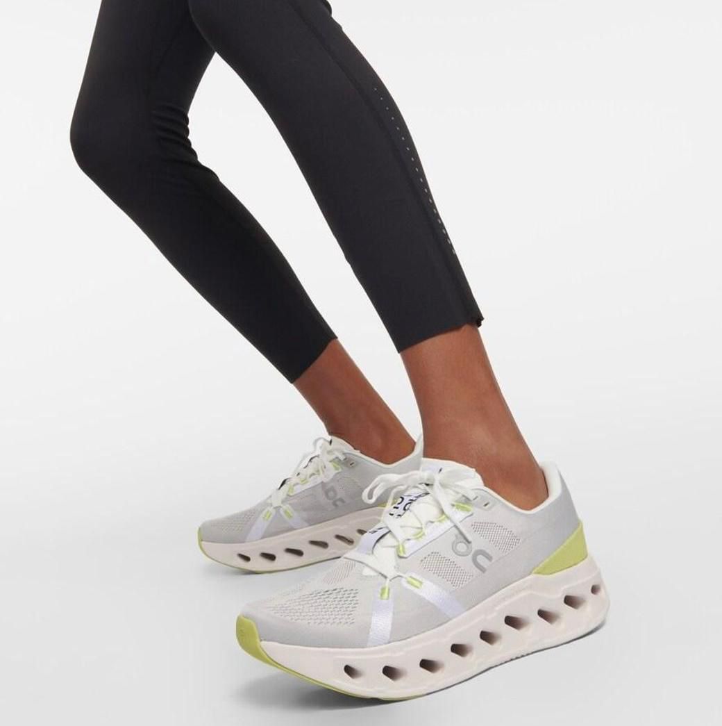 WhatsApp_Image_2025-01-18_at_13.18.14 | AE JERSEY Athletic white and light gray sneakers with lime accents and a perforated chunky sole being worn with black leggings by a person walking forward.