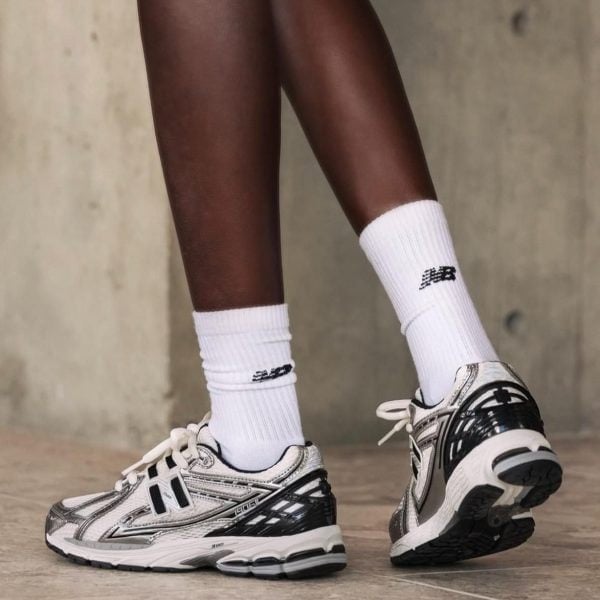 Person wearing white crew socks and silver-gray running shoes standing on a concrete floor.