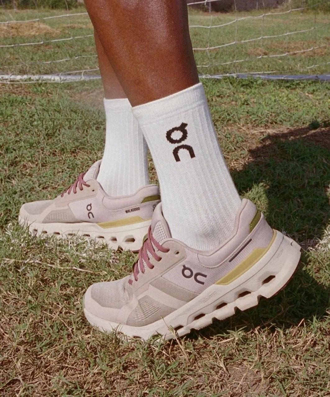 WhatsApp_Image_2025-02-25_at_14.00.34 | AE JERSEY Person wearing white athletic socks with a logo and light pink sneakers on grass outdoors.