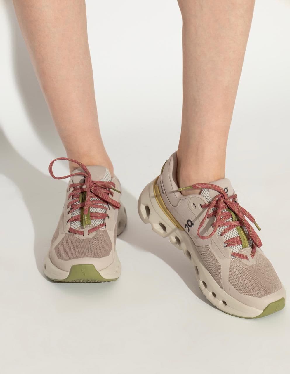 WhatsApp_Image_2025-02-25_at_14.00.41 | AE JERSEY Beige athletic sneakers with pink laces on a person’s feet, standing against a white background.