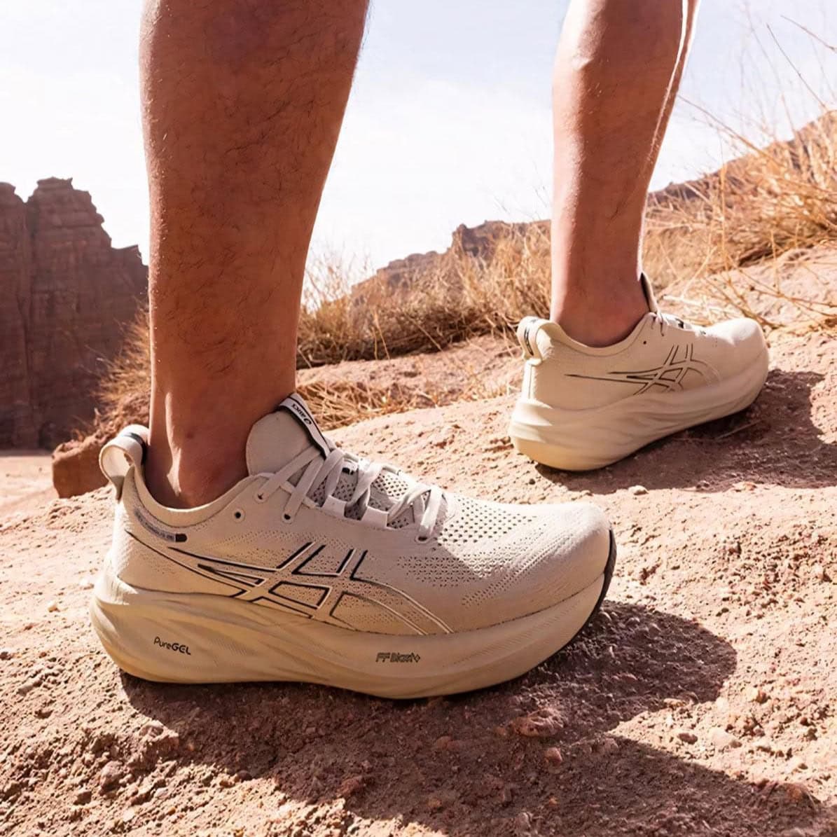 WhatsApp_Image_2025-02-26_at_10.26.57 | AE JERSEY Person wearing light-colored athletic running shoes on rocky desert trail, mid-step on a dusty path with dry grasses in the background.