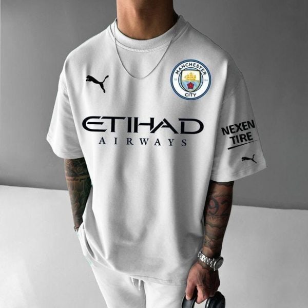 Person wearing a white Manchester City football jersey with Etihad Airways sponsor and club crest on the chest, plus Puma logos and a sponsor on the sleeve.