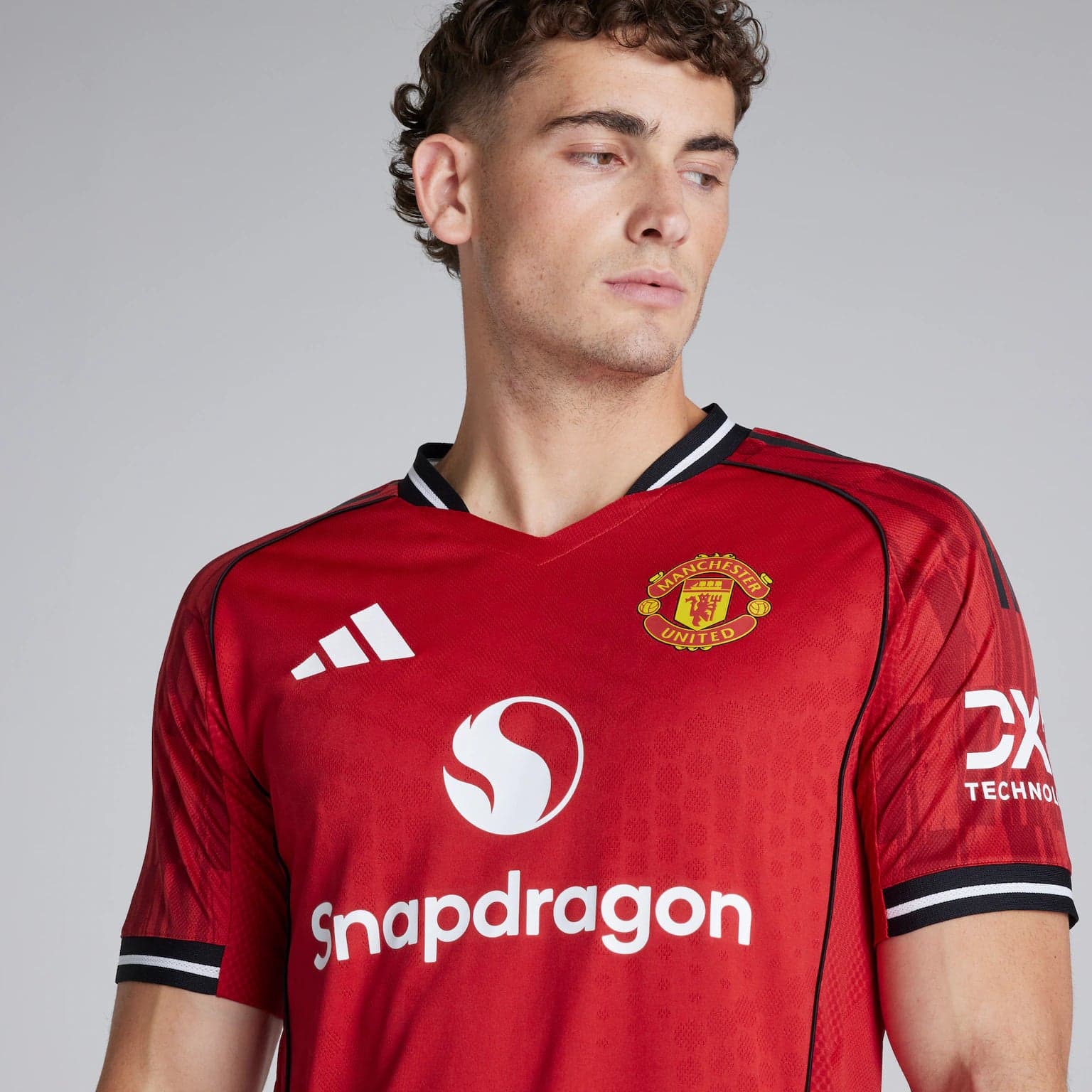 a04f031b36b5cd30ff12deca84a5be84 | AE JERSEY Man wearing a red Manchester United soccer jersey, facing slightly to the right, showing the team crest and Snapdragon sponsor text on the chest.