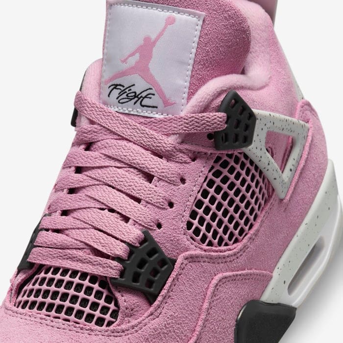 a87b0230_9568_4098_b0d5_a24b8c146d23 | AE JERSEY Close-up of a pink Air Jordan 4 sneaker, showing suede upper, pink laces, mesh panels, and black wing eyelets with a Jumpman logo on the tongue.