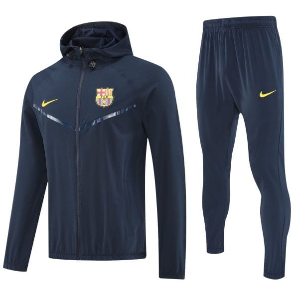Navy blue FC Barcelona training jacket with crest and yellow Nike swoosh, alongside matching navy pants with a yellow Nike logo.