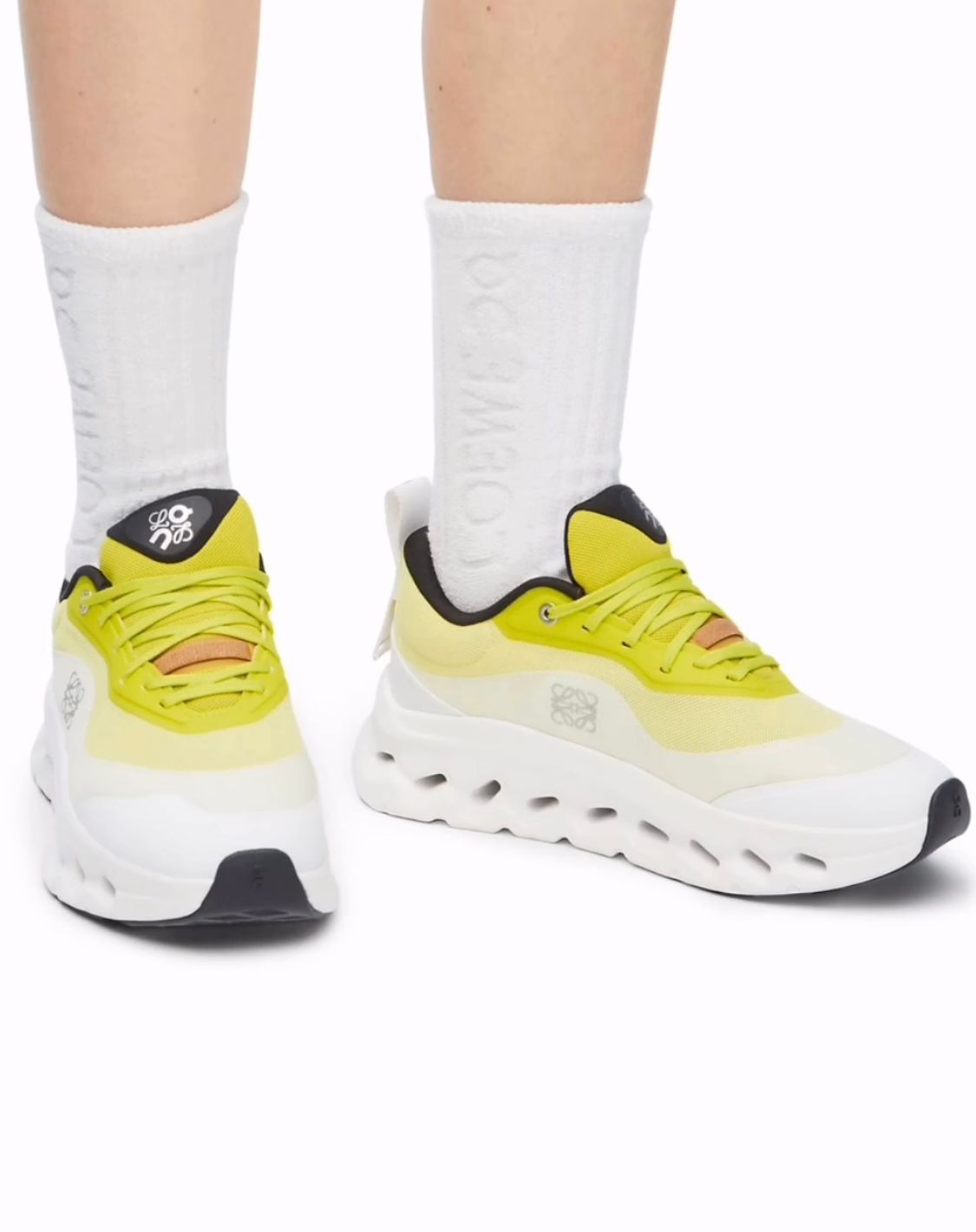 ac768573-7bad-4268-8532-3520aea43936 | AE JERSEY Yellow athletic sneakers with a chunky white sole on both feet, paired with white crew socks and black heel accents on the shoes.