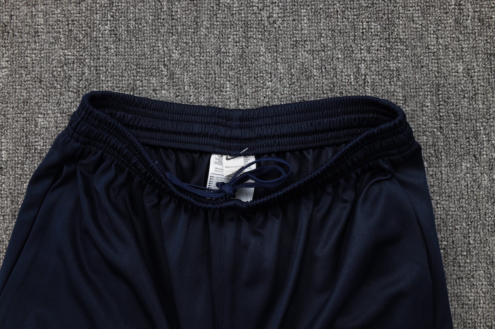 b2fb6097 | AE JERSEY Navy blue pants with an elastic waistband and drawstring on a gray carpet, tag visible between the fabric edges.