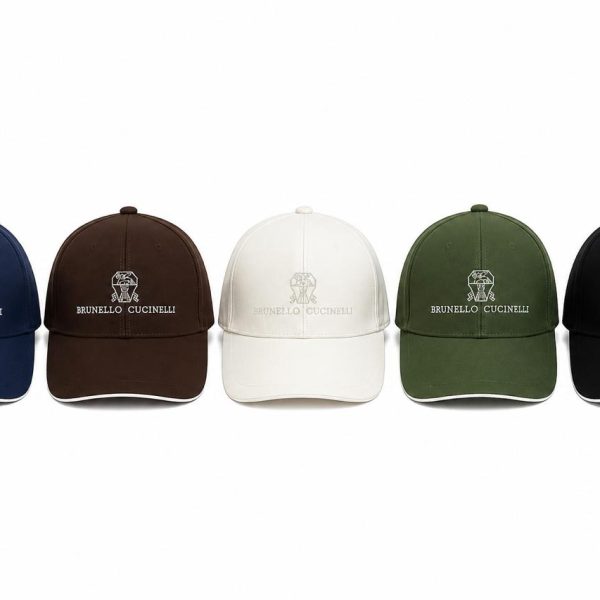 Five Brunello Cucinelli baseball caps in navy, brown, white, olive, and black, each with an embroidered logo lined up front.