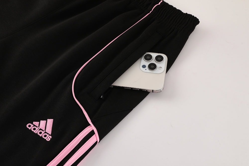bac4ab3c | AE JERSEY Black Adidas track pants with pink piping; a smartphone sticks out of the back pocket.