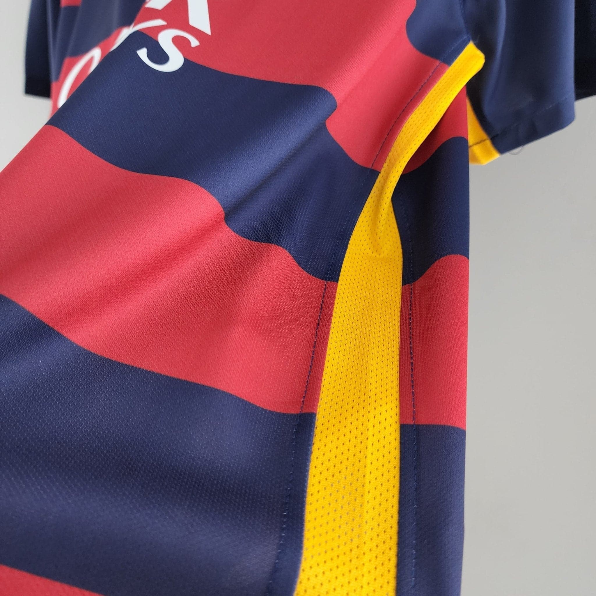 barcelona-classic-201516-final-with-messi-10-badges-jersey-333485 | AE JERSEY Close-up of a sports jersey with red and blue panels and a yellow strap/trim visible along the edge.