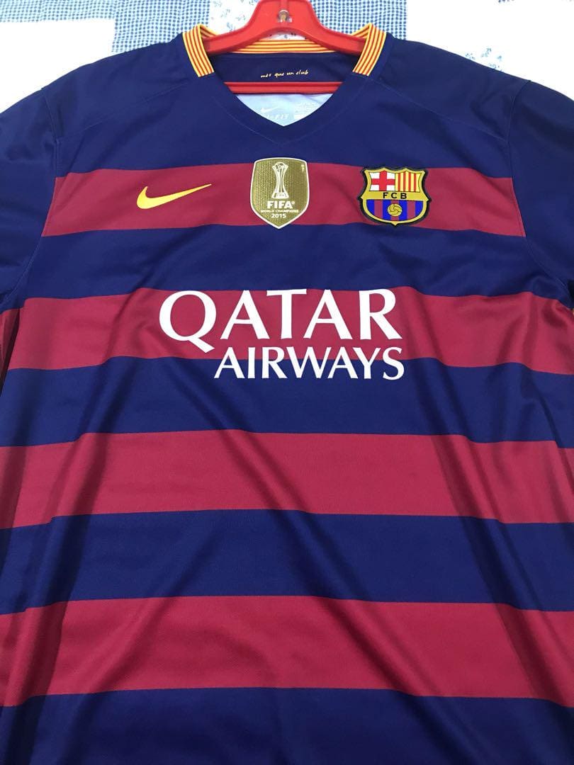 barcelona-classic-201516-final-with-messi-10-badges-jersey-348531 | AE JERSEY FC Barcelona football jersey on a hanger: blue and maroon horizontal stripes, yellow Nike swoosh, Barça crest, FIFA badge, Qatar Airways sponsor.