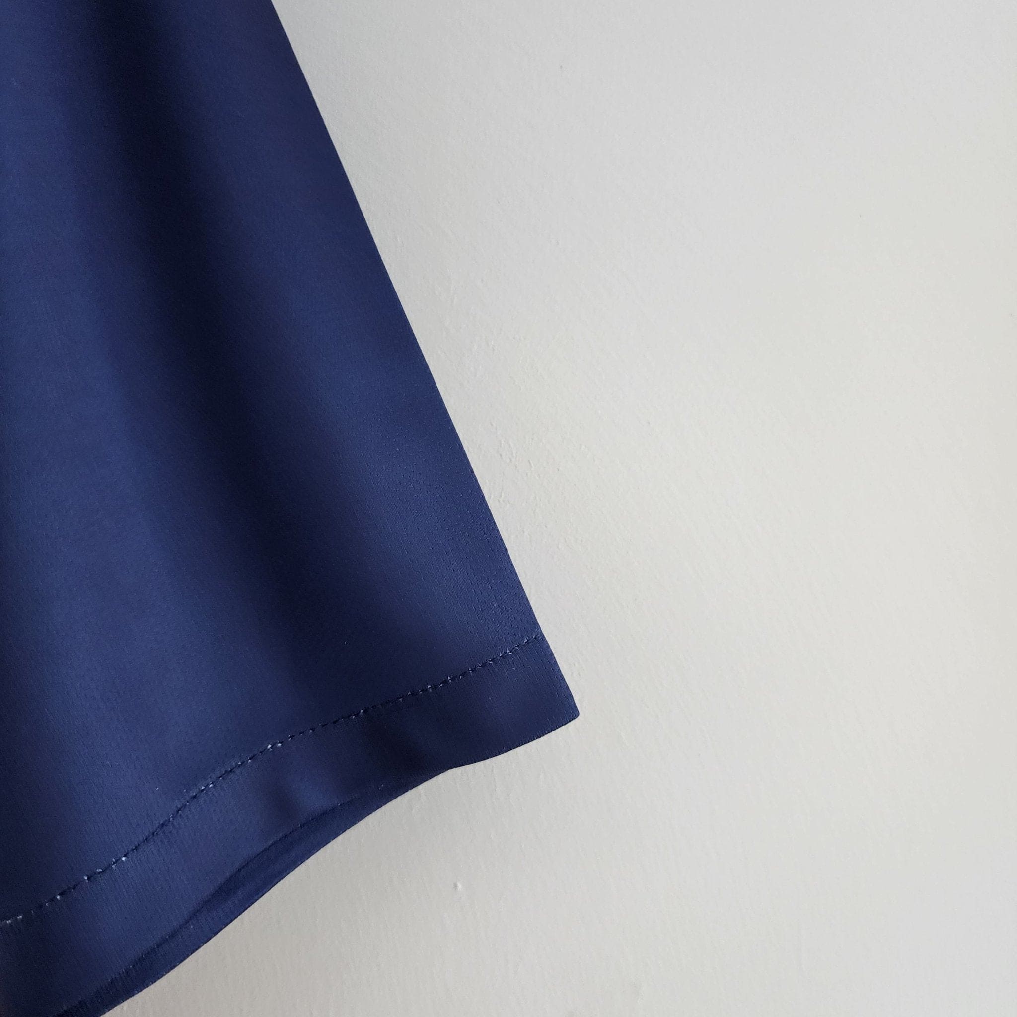 barcelona-classic-201516-final-with-messi-10-badges-jersey-542967 | AE JERSEY Close-up of blue fabric with visible stitching along the edge against a white background.