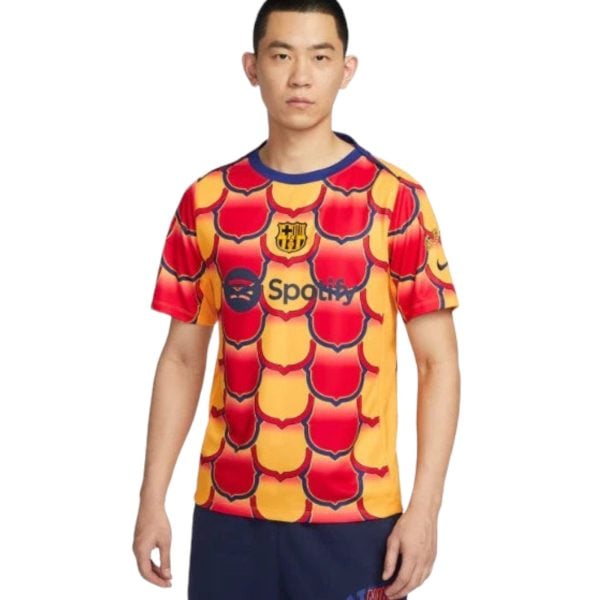 Front view of a man wearing a bright red and yellow patterned FC Barcelona soccer jersey with a blue collar and sponsor logo on the chest (Spotify).