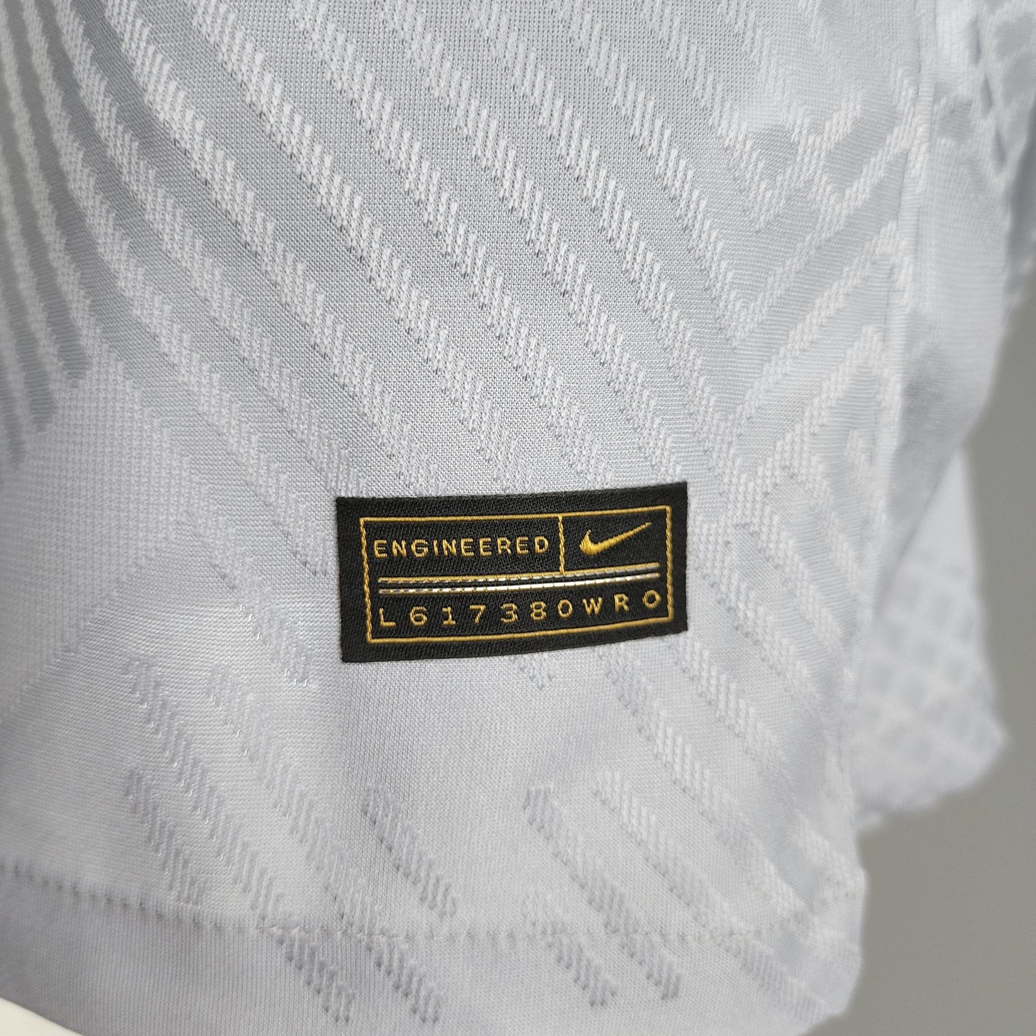 barcelona-third-player-version-jersey-202223-270283 | AE JERSEY Close-up of gray knit fabric with a black label reading 'ENGINEERED' and yellow stitching.
