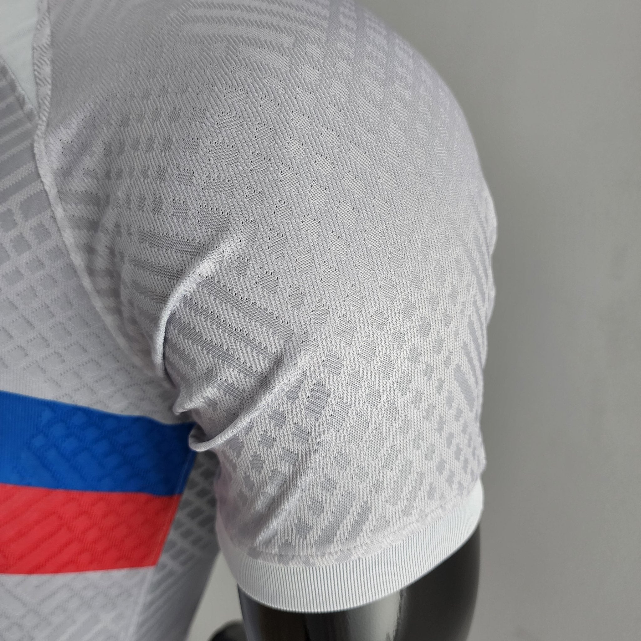 barcelona-third-player-version-jersey-202223-468084 | AE JERSEY Close-up of gray patterned fabric with a blue and red stripe at the edge.
