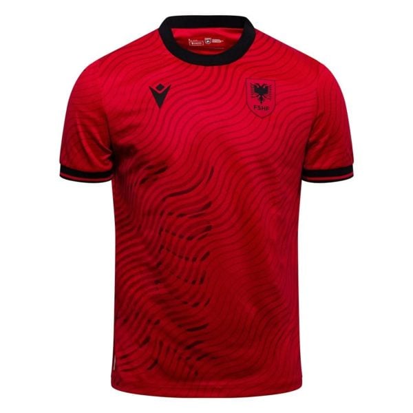 Red football jersey with black wavy pattern, black collar, Albanian Football Association crest on left chest and a black MACRON logo on the right chest