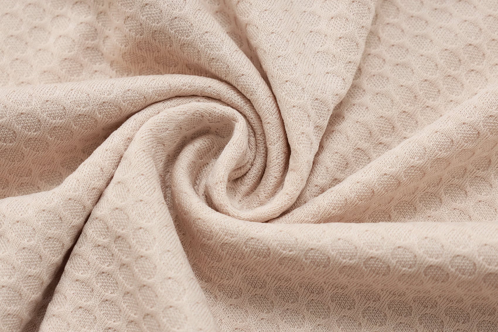 c0159c70 | AE JERSEY Beige textured fabric with a circular dot pattern, folded in soft spirals.