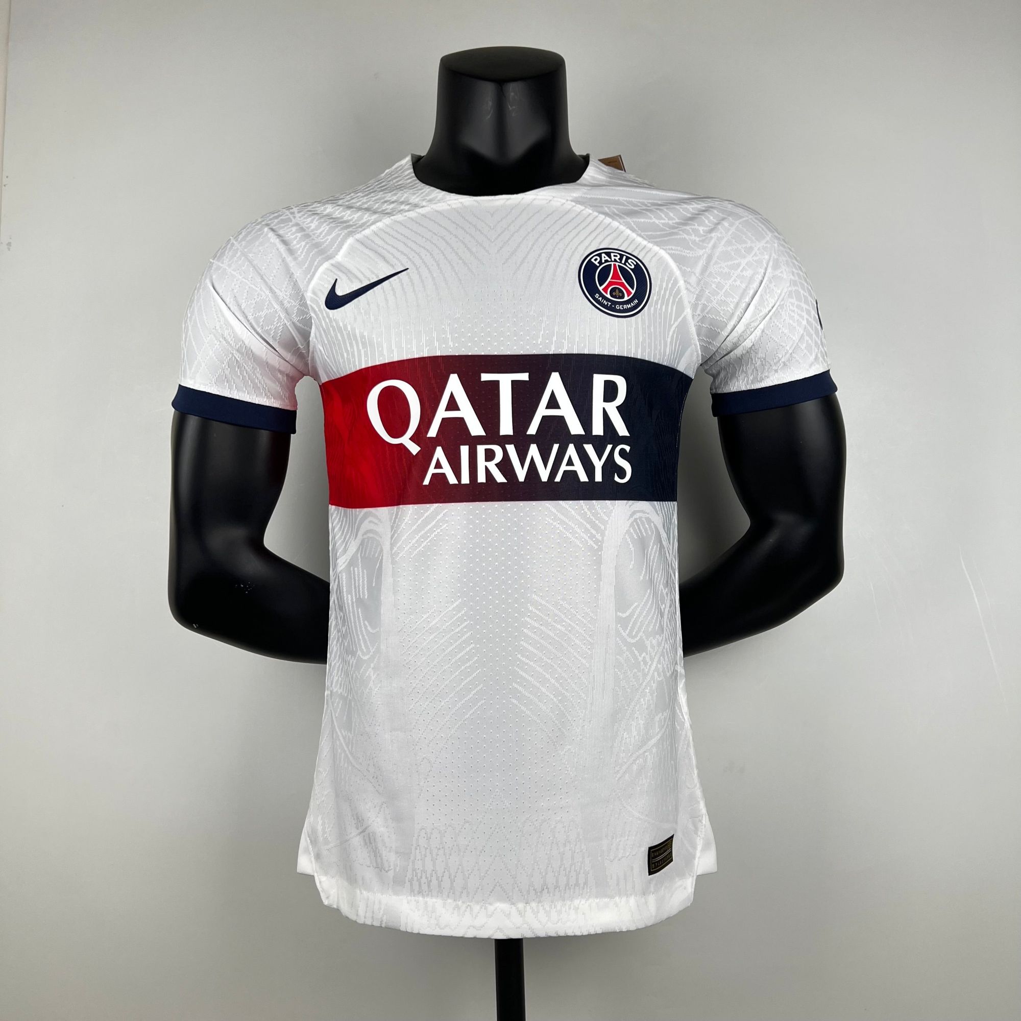 c051d1f9_86db660b-b5e2-4307-99eb-4aa1d4d5a917 | AE JERSEY Mannequin wearing a white Paris Saint-Germain jersey with Qatar Airways sponsor, Nike swoosh, and PSG crest on the chest.