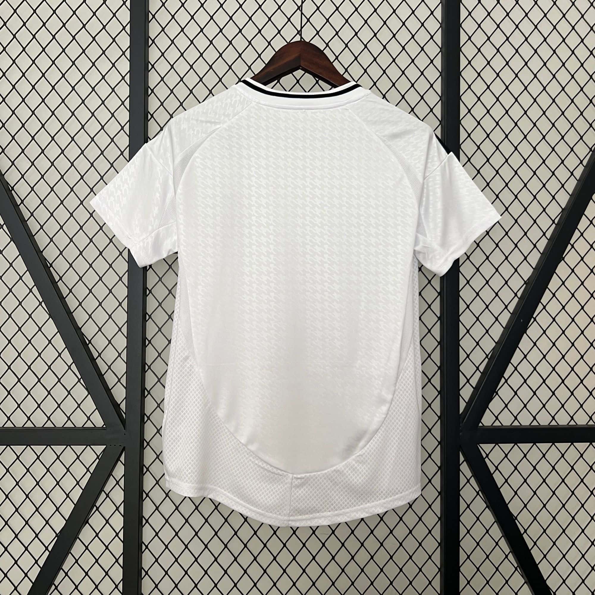 c0e7558c | AE JERSEY White short-sleeve shirt on a wooden hanger, displayed against a diamond-pattern metal grid backdrop, with subtle textured pattern on fabric.