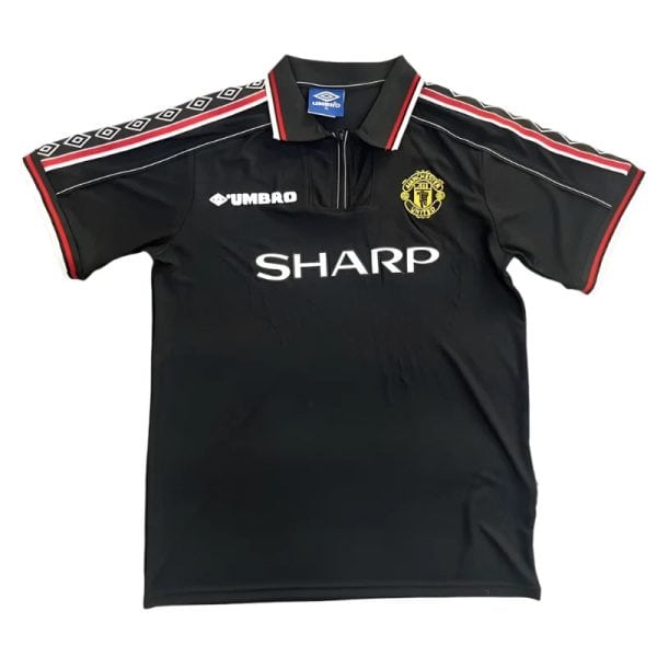 Black Manchester United football jersey with SHARP sponsor, Umbro logo, and club crest on the chest; red and white piping on sleeves.