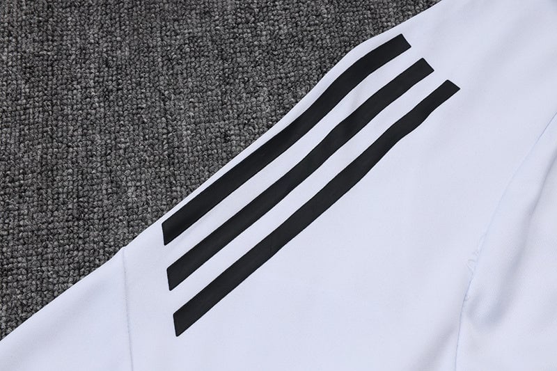 ccbcdada | AE JERSEY White sports sleeve on a gray carpet with three black stripes along the shoulder area (Adidas-style).