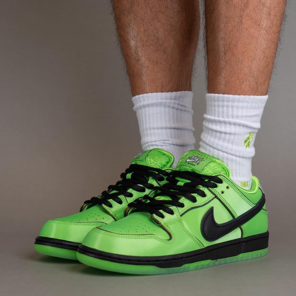 cee68df7-601b-48cf-ab7b-03222c6dec4b | AE JERSEY Bright neon green Nike sneakers with a black swoosh and white socks, standing on a gray background.