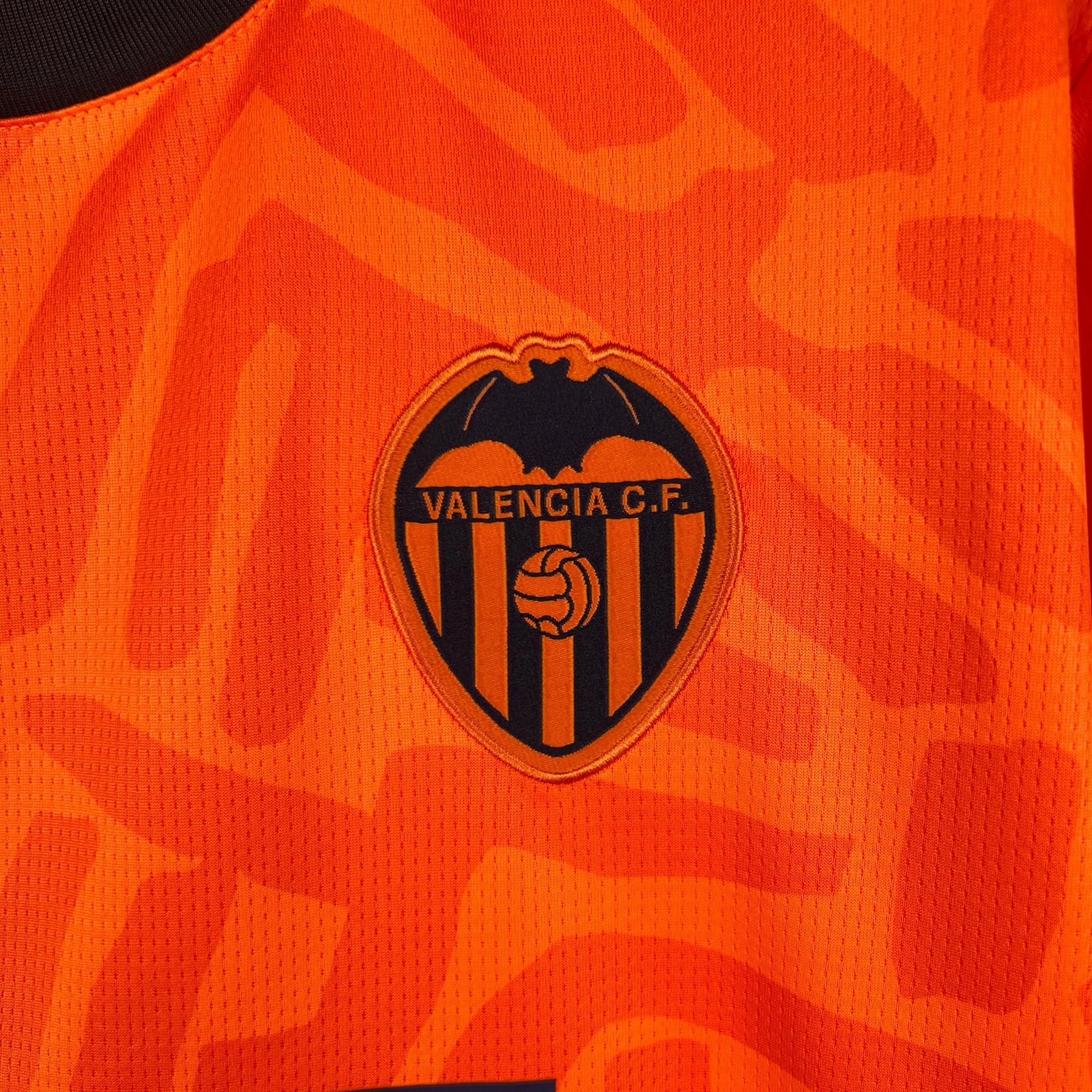 cf373f5d_2b1ef9b1-1799-468d-9228-12a346badf78 | AE JERSEY Close-up of orange Valencia CF jersey fabric with partial crest and text Valencia C.F.