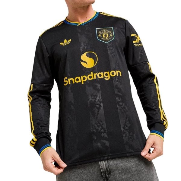 Black Manchester United long-sleeve football jersey with Snapdragon sponsor and yellow accents worn by a person