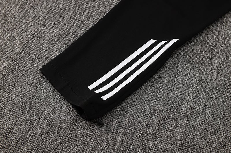 d86a7bf4 | AE JERSEY Black track pants leg with three white stripes along the side on a gray carpeted floor.