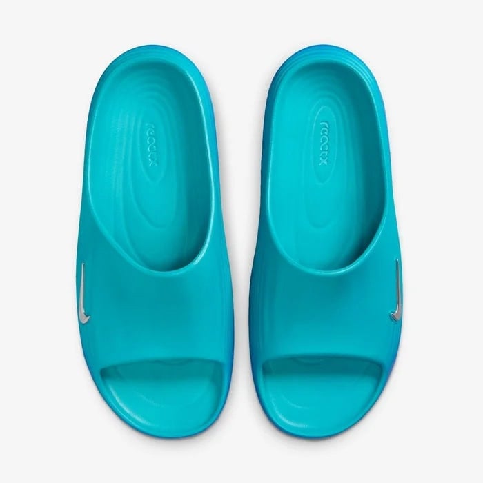 ded77c76_8543_43fd_a670_72920b79b00b | AE JERSEY Top-down view of a pair of turquoise slide sandals with a small Nike swoosh on each strap.