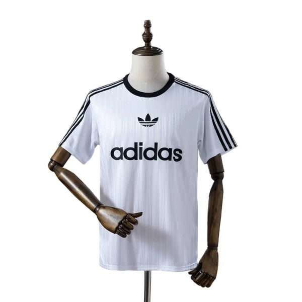 White Adidas T-shirt on a mannequin with black trefoil logo and three black stripes along sleeves.
