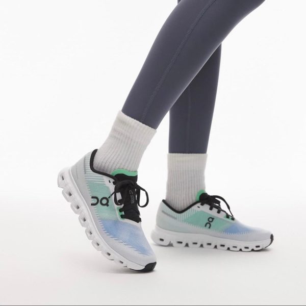 Person wearing pastel gradient On running shoes (blue to mint) with white cushioned sole, gray leggings, and white crew socks on a white background.