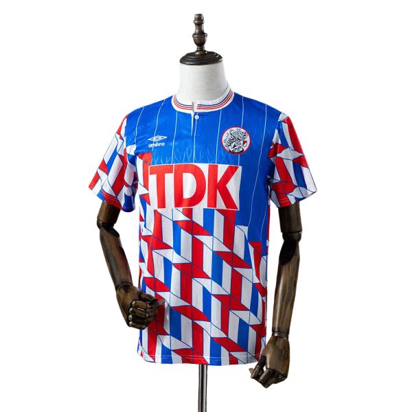 Blue, red, and white geometric soccer jersey on a dress form with a crest and 'TDK' sponsor across the chest.