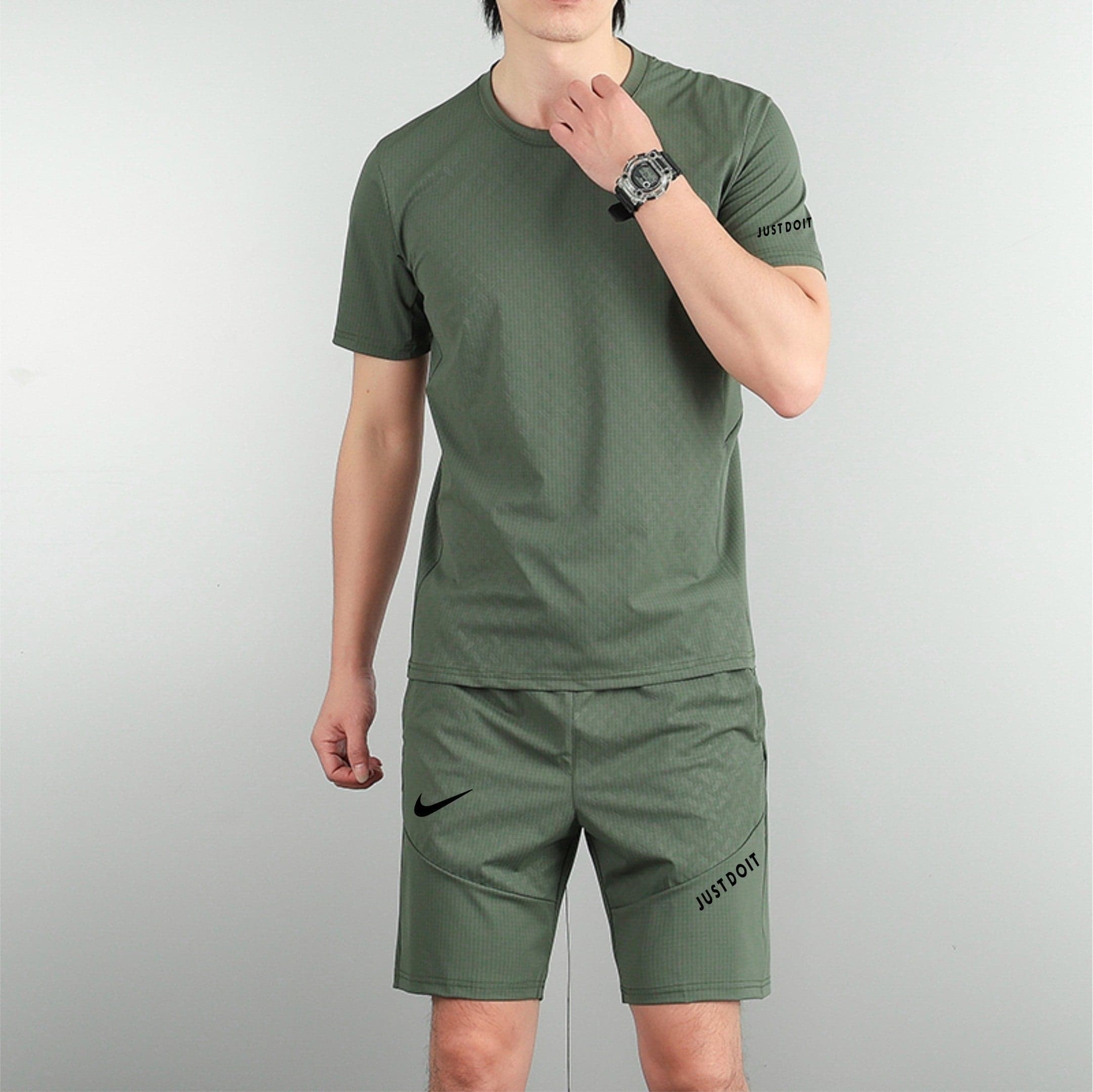 f572574b | AE JERSEY Partial body of a man in olive-green athletic wear against a gray backdrop, with visible Nike swoosh on shorts and 'JUST DO IT' text on the leg.