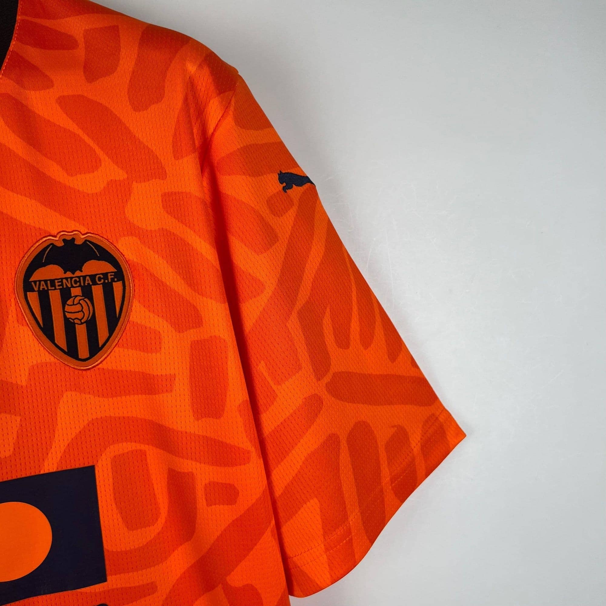 f6a8baff_1_f830b074-75de-427f-8ba2-b44f010dff79 | AE JERSEY Close-up of an orange Valencia CF football jersey, showing the club crest on the chest.