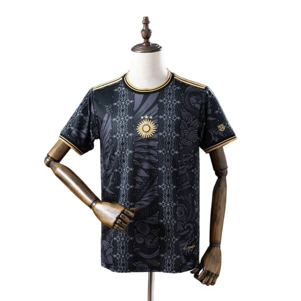 Black patterned sports jersey with gold trim on collar and sleeves, displayed on a mannequin; features a gold sun emblem at center.