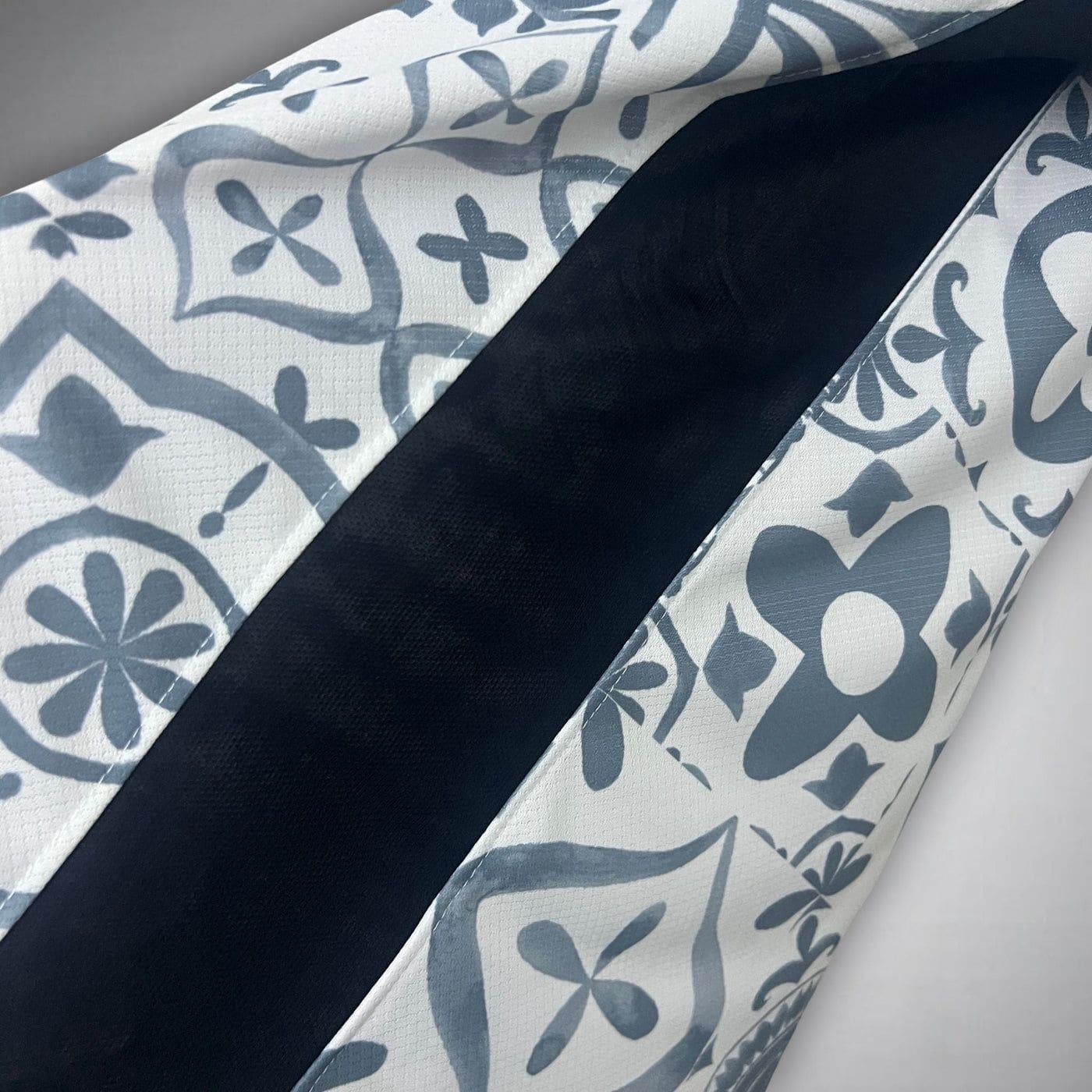 fd93b265-991f-4fdd-b82b-bad186bf5e99 | AE JERSEY Close-up of white fabric with a blue floral pattern and a dark navy seam running diagonally across the image.