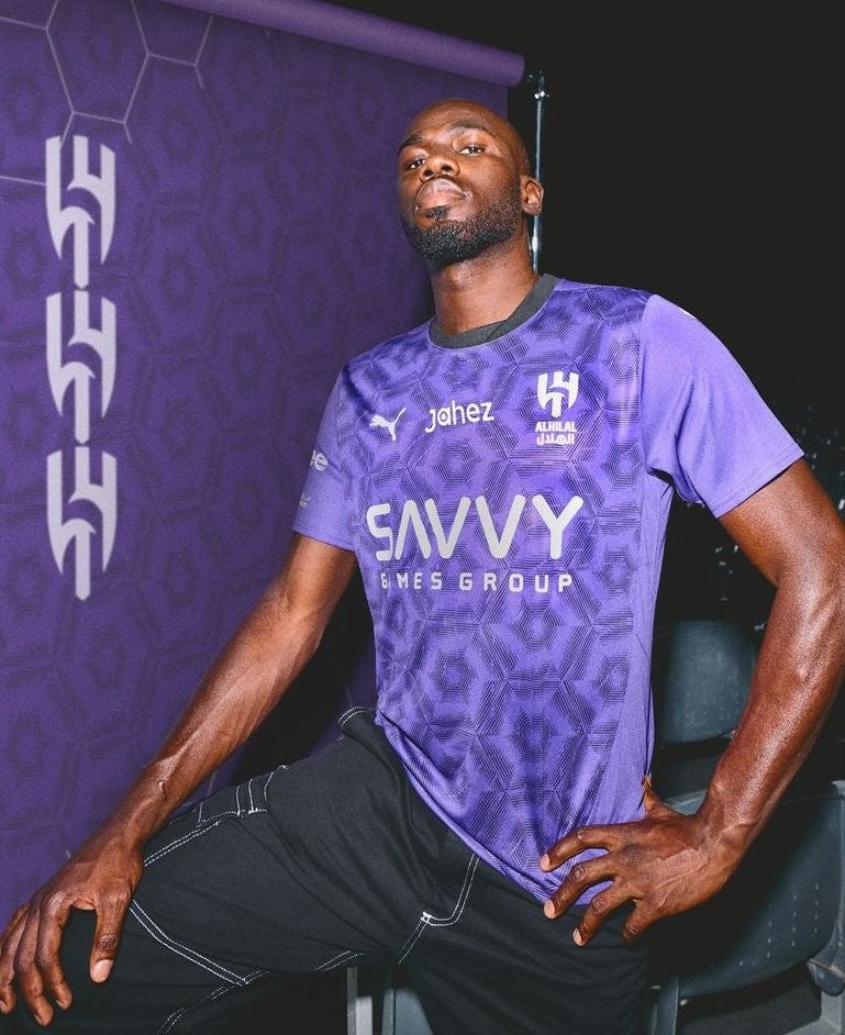 fmGwlE4KfHzHmTe | AE JERSEY Athlete in a purple SAVVY Games Group jersey posing with one hand on his hip against a purple backdrop