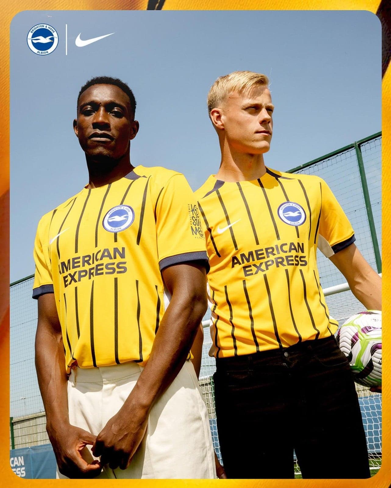gVRQdEuMEm0gdDW | AE JERSEY Two football players in yellow striped jerseys stand side by side outdoors, posing with a clear blue sky behind them and a green fence in the background.