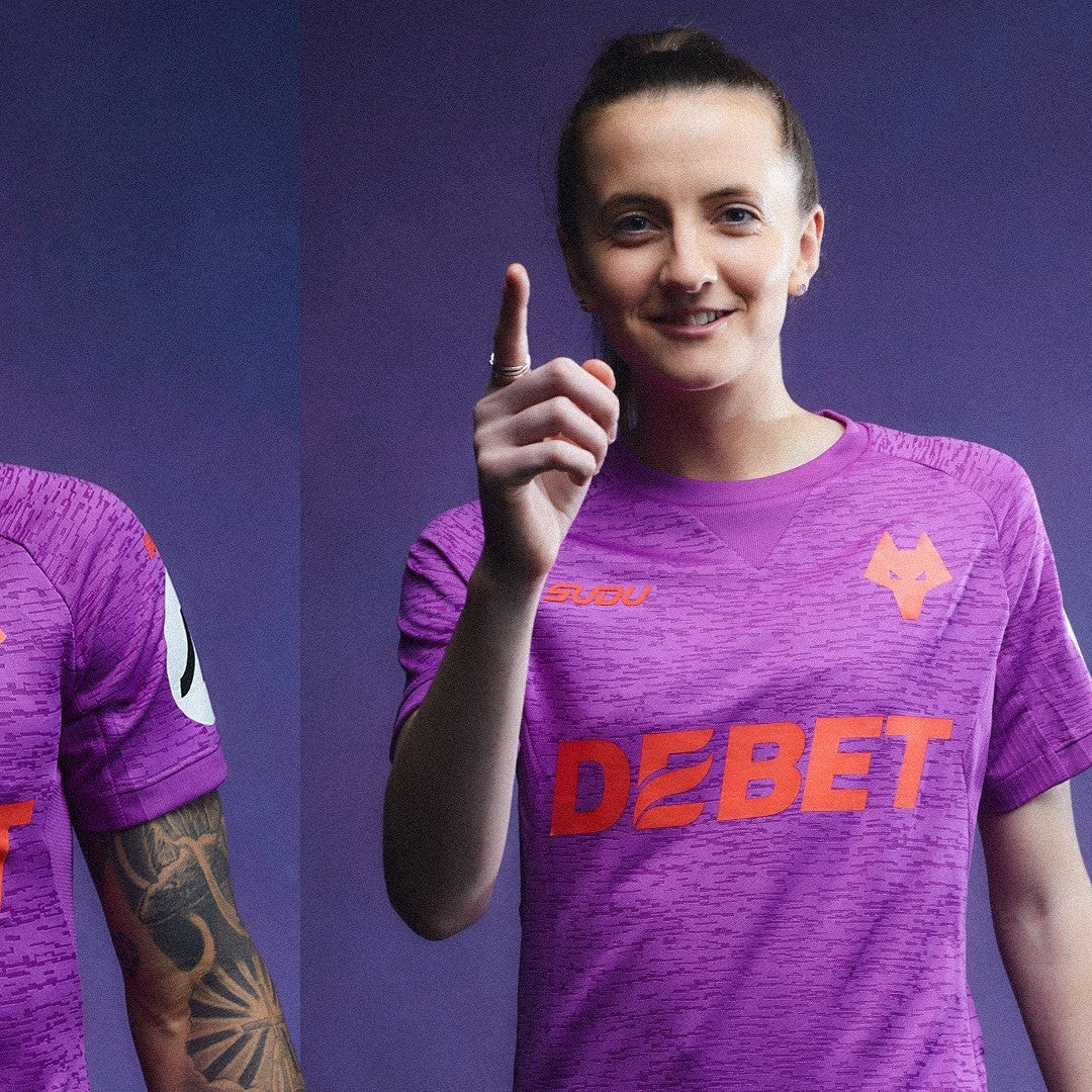 ihu4P0wU56xpPCp | AE JERSEY Smiling woman in a purple team jersey points toward the viewer, against a purple background.